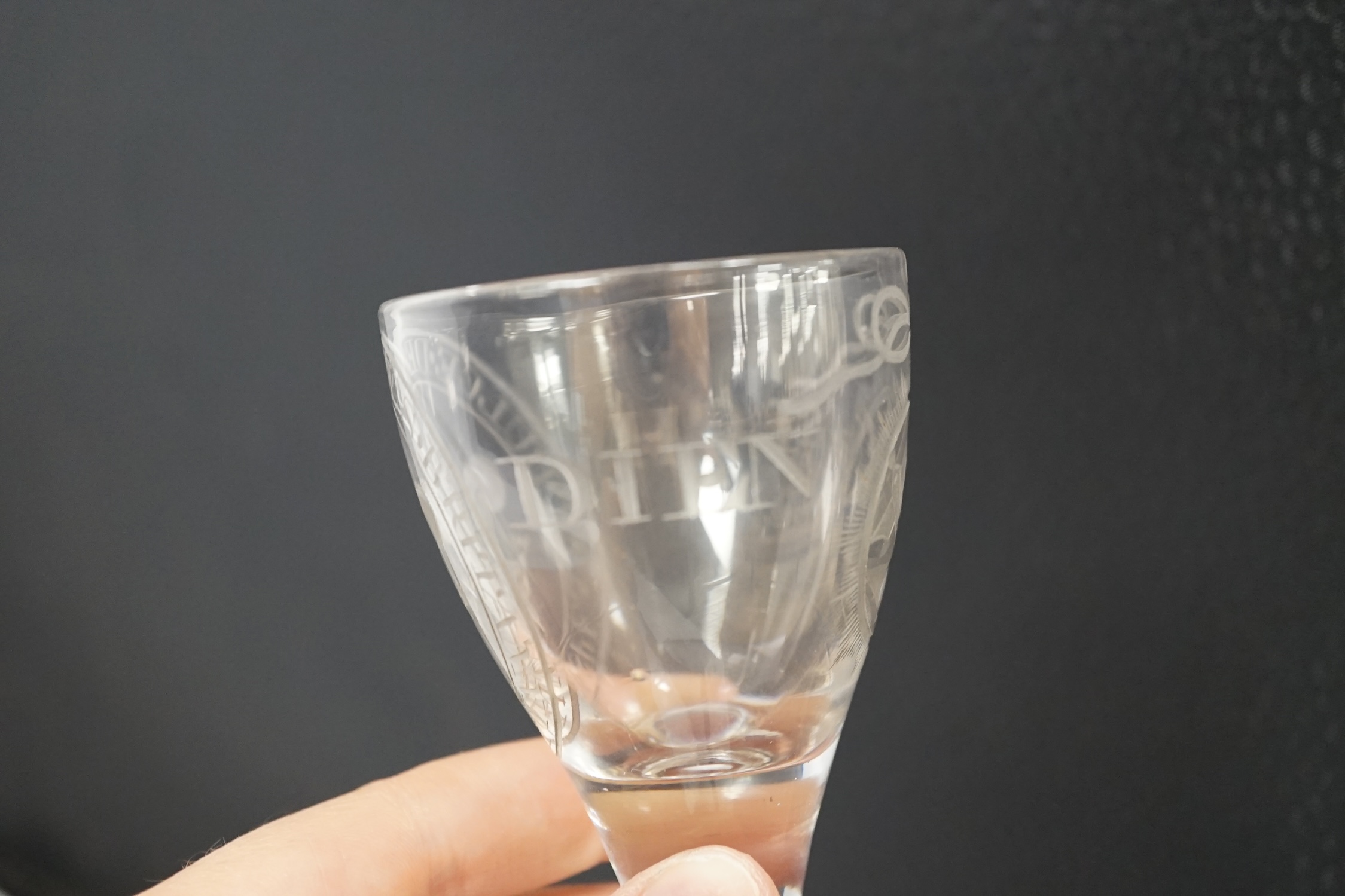 A George III Prince of Wales commemorative firing glass, early 19th century, finely wheel engraved with the Prince of Wales feathers, the motto ‘Spes. et. Dulce. Decus. Britannia’, ‘Ich Dien’ and Masonic motifs, 10.5cm h